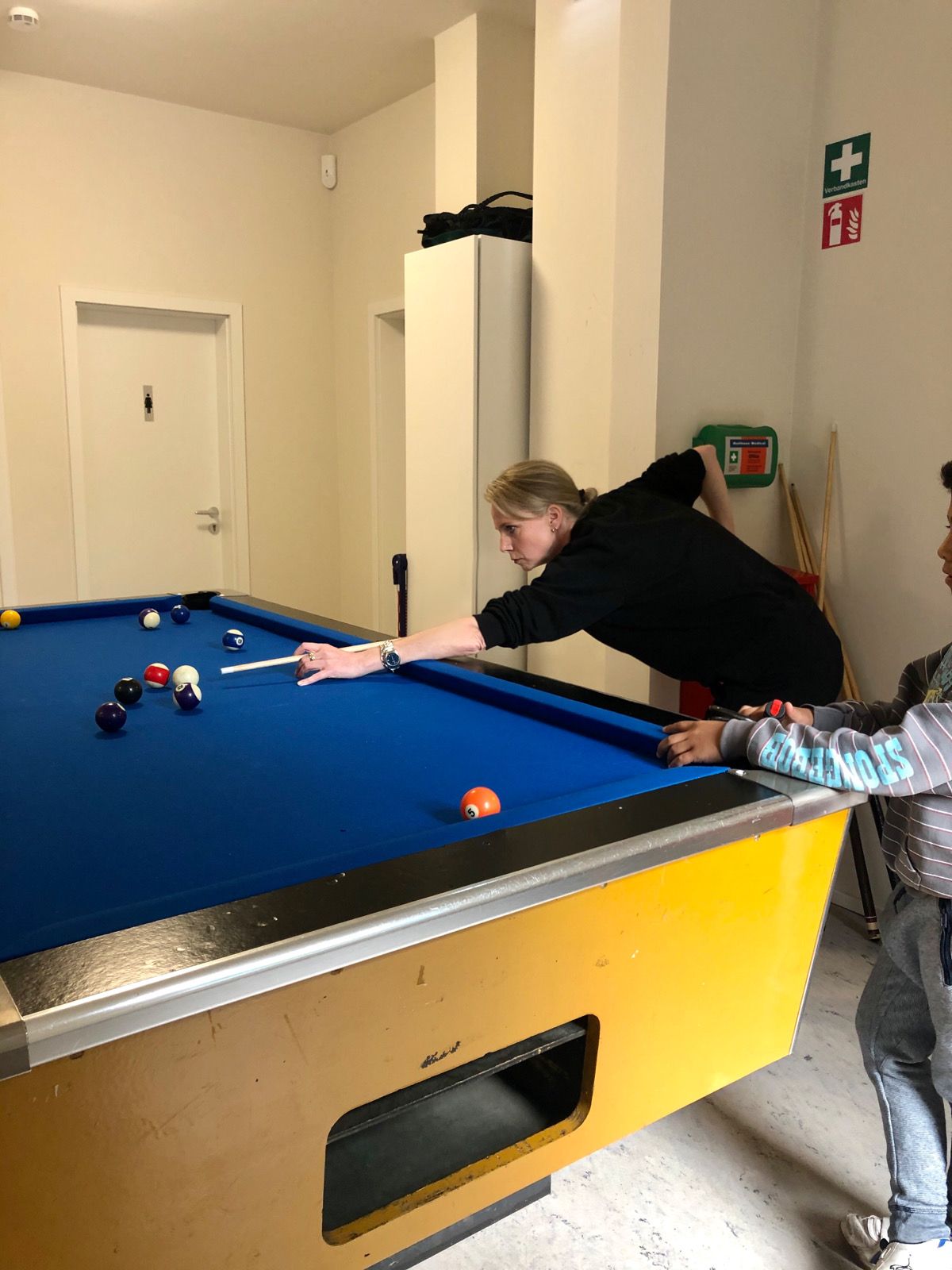 Foto: Betreuerin und Jugendlicher beim Billardspielen